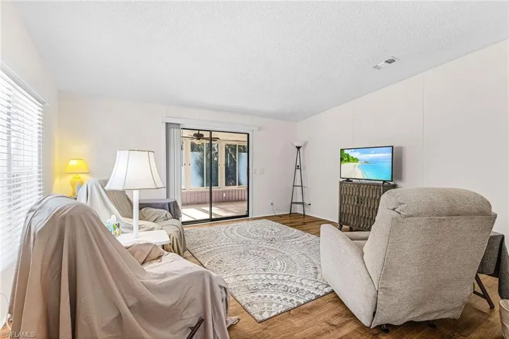 Living area with vaulted ceiling, a textured ceiling, plenty of natural light, and wood finished floors