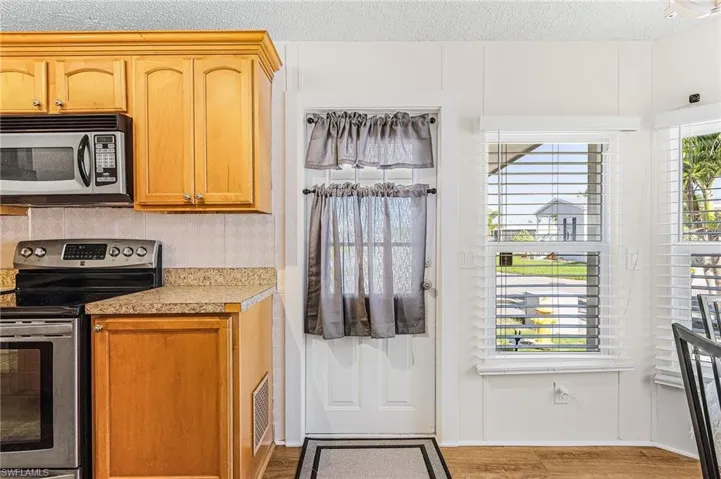 Kitchen with appliances with stainless steel finishes, light wood-type flooring, decorative backsplash, and light countertops