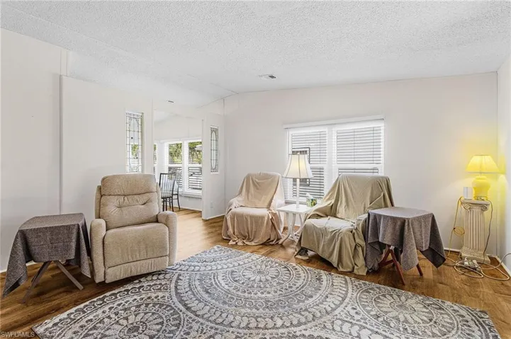 Sitting room with wood finished floors, a textured ceiling, and lofted ceiling