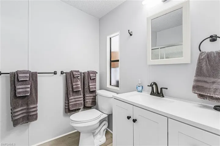 Bathroom with a textured ceiling, vanity, and wood finished floors