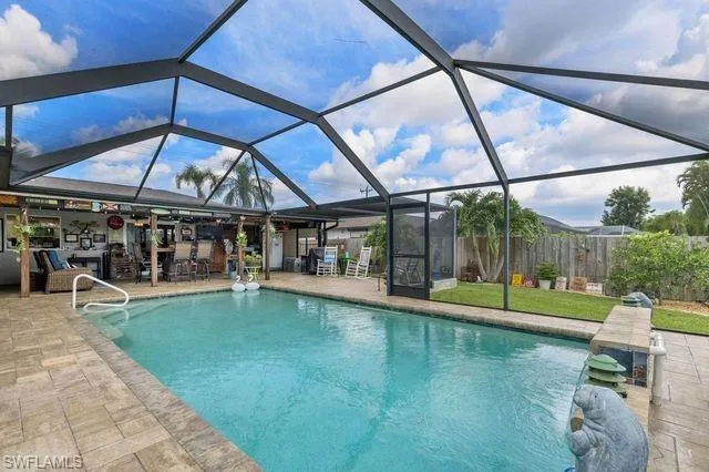View of pool with glass enclosure and a patio area