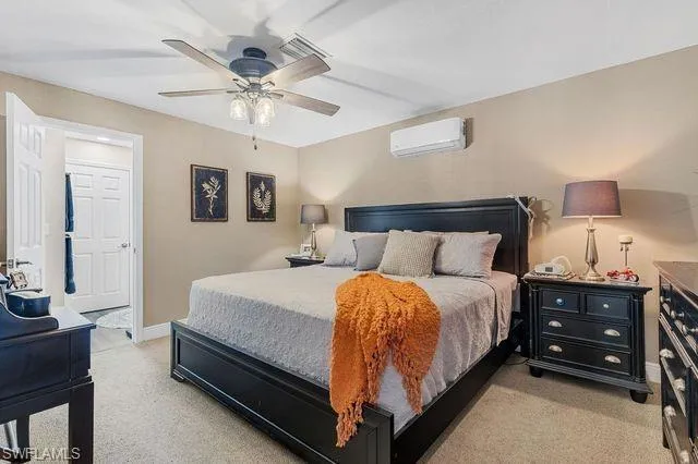 Carpeted bedroom featuring a wall unit AC and ceiling fan