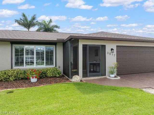 Single story home with a garage and a front lawn