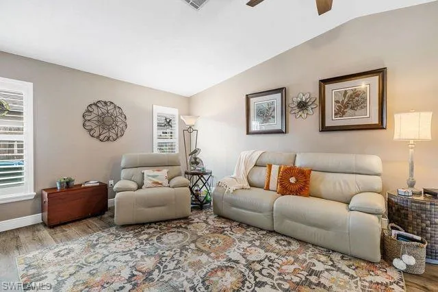 Living room with hardwood / wood-style flooring, ceiling fan, and vaulted ceiling