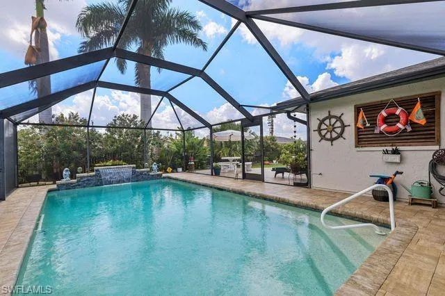 View of swimming pool with pool water feature, glass enclosure, and a patio