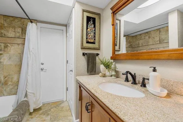 Bathroom featuring tile floors, shower / bath combo, and large vanity