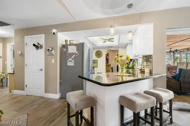 Kitchen featuring white cabinets, stainless steel refrigerator, kitchen peninsula, and hardwood / wood-style flooring