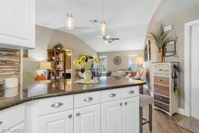 Kitchen with hanging light fixtures, ceiling fan, light hardwood / wood-style flooring, and white cabinetry