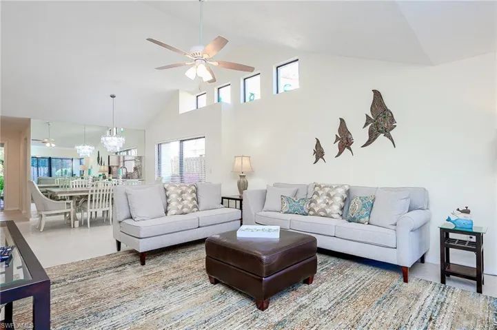 Living room featuring a ceiling fan, high vaulted ceiling, and a chandelier