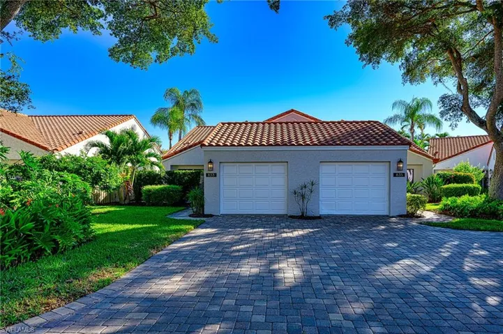 View of front of house with a tile roof, stucco siding, decorative driveway, a garage, and a front lawn