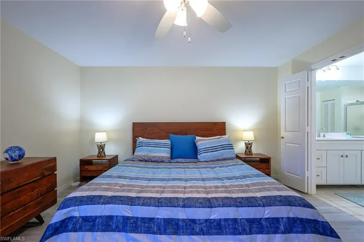 Bedroom featuring ceiling fan, wood finished floors, and ensuite bathroom