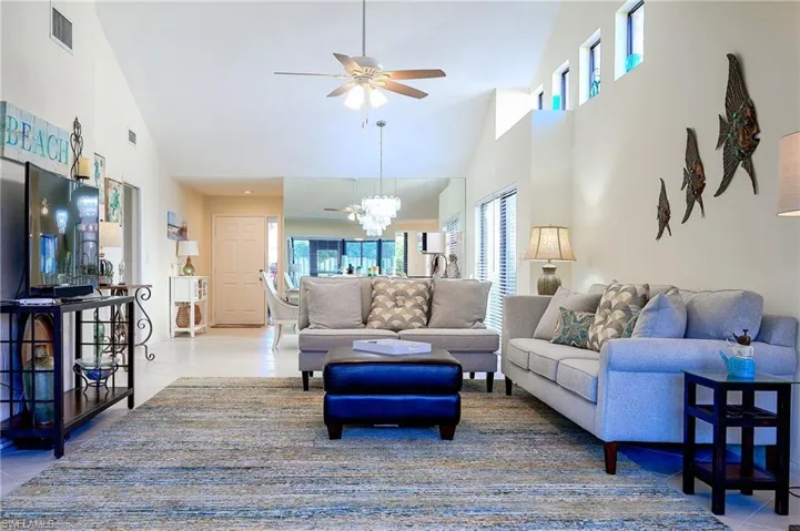 Living area with light tile patterned floors, ceiling fan, a chandelier, and high vaulted ceiling