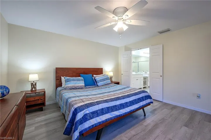 Bedroom with wood finished floors, ceiling fan, and connected bathroom