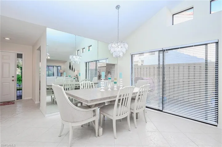 Dining room with plenty of natural light, a chandelier, lofted ceiling, and light tile patterned flooring