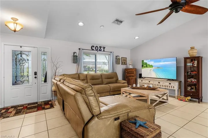 Living room with visible vents, light tile patterned flooring, recessed lighting, ceiling fan, and vaulted ceiling