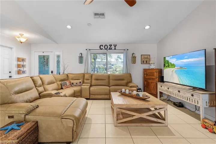 Living area with a ceiling fan, visible vents, lofted ceiling, light tile patterned flooring, and recessed lighting
