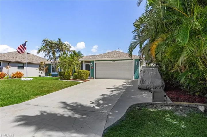Ranch-style home featuring a front yard, an attached garage, driveway, and stucco siding