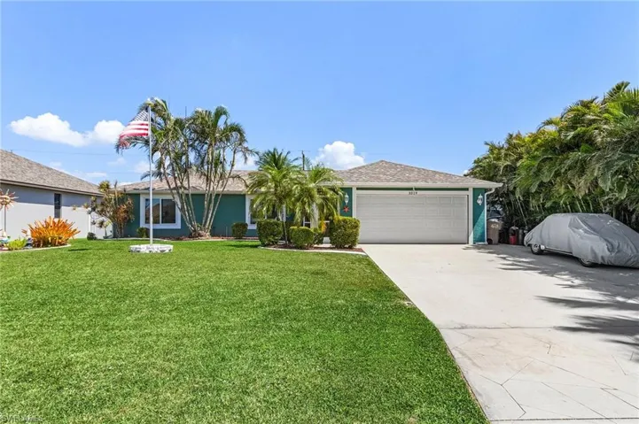 Ranch-style house with a garage, concrete driveway, a front lawn, and stucco siding