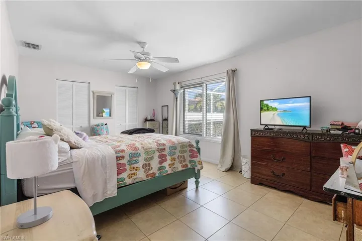 Bedroom featuring light tile patterned floors, a ceiling fan, visible vents, and two closets