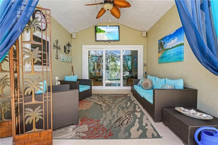 Living room with vaulted ceiling, a textured wall, and ceiling fan