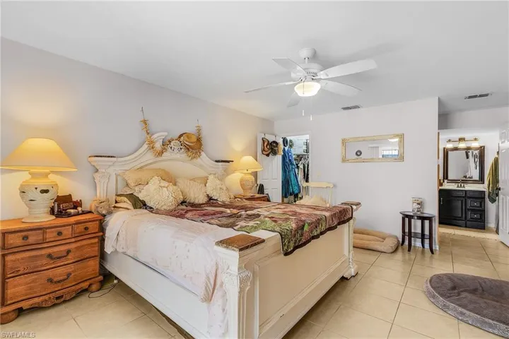 Bedroom featuring visible vents, ensuite bath, light tile patterned flooring, a closet, and a walk in closet