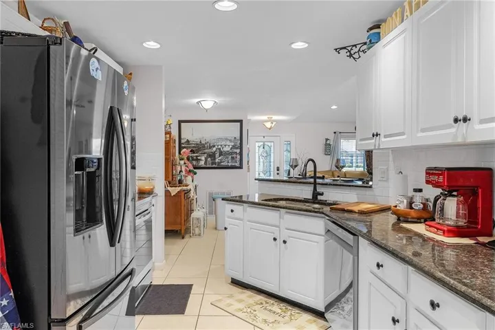 Kitchen with a sink, stainless steel appliances, a peninsula, and white cabinets