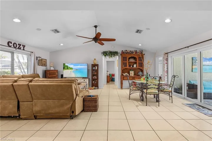 Living room featuring light tile patterned floors, visible vents, and vaulted ceiling