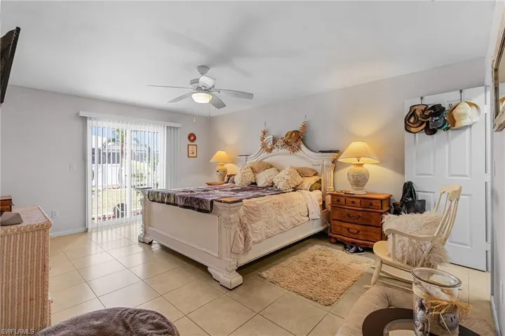 Bedroom with light tile patterned floors, baseboards, access to exterior, and a ceiling fan