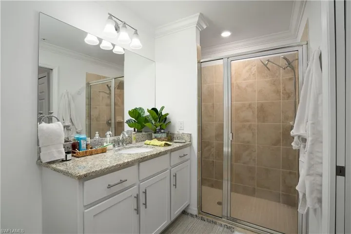 Bathroom with vanity, crown molding, and walk in shower