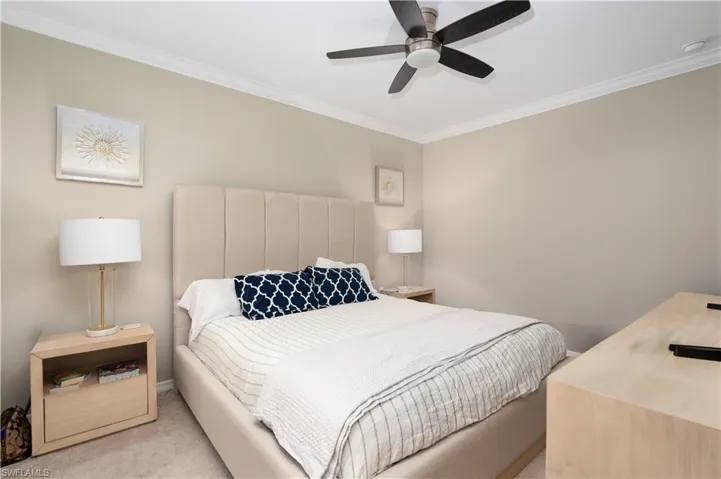 Bedroom with ceiling fan, crown molding, and light carpet