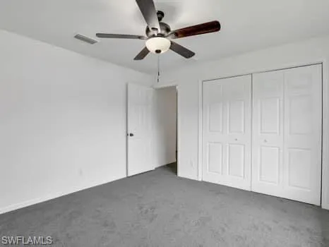 Unfurnished bedroom featuring carpet flooring, ceiling fan, and a closet