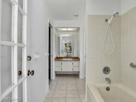 Full bath featuring shower / bathtub combination, vanity, and light tile patterned flooring