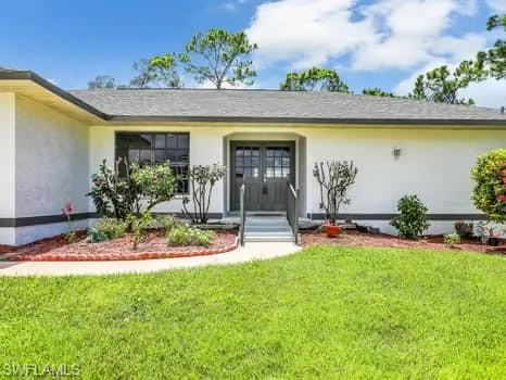 Doorway to property with a yard and stucco siding