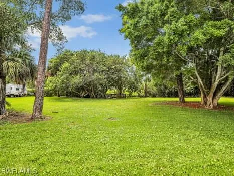 View of green lawn featuring view of scattered trees