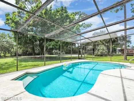 Outdoor pool featuring a yard, a lanai, and a sunroom