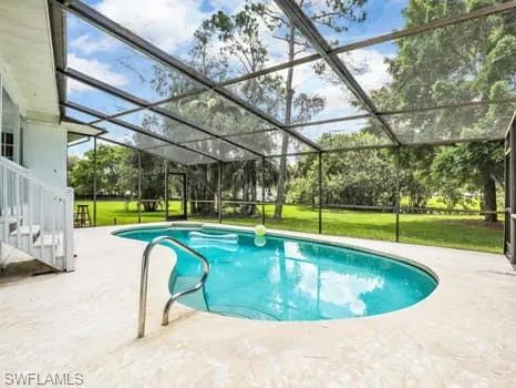 Swimming pool featuring a sunroom, a lanai, and a patio