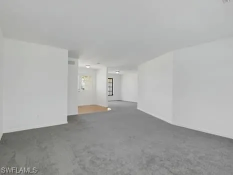 Carpeted spare room featuring baseboards