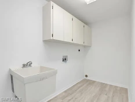 Laundry room featuring hookup for a washing machine, light wood-style floors, electric dryer hookup, and cabinet space
