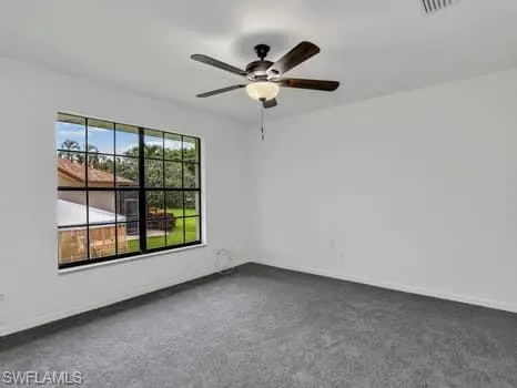 Empty room featuring ceiling fan and dark carpet