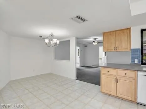 Kitchen with light brown cabinets, white dishwasher, open floor plan, a ceiling fan, and a chandelier