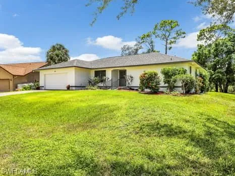 Single story home with an attached garage and a front lawn