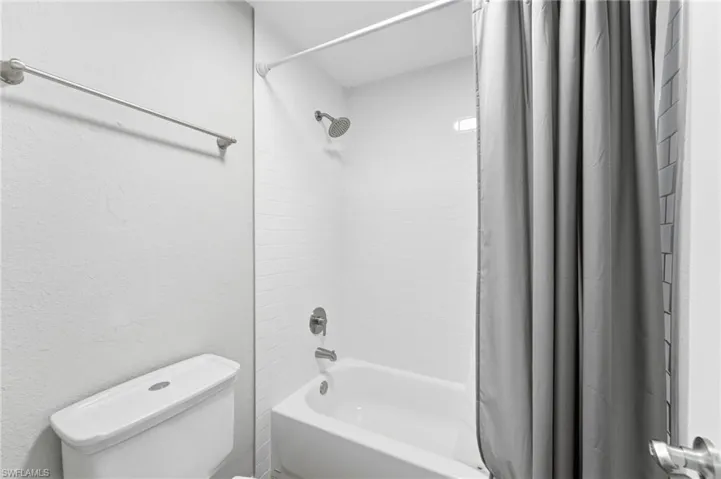 Full bathroom with shower / tub combo with curtain and toilet