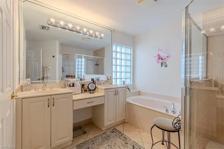 Bathroom with a stall shower, light tile patterned floors, a bath, and double vanity