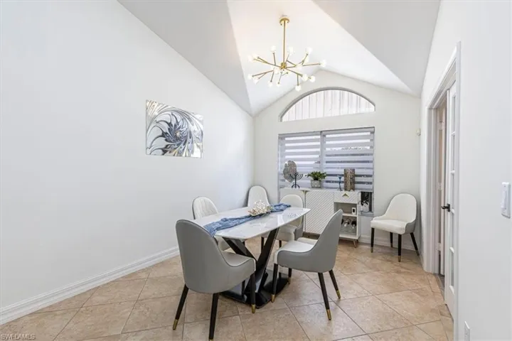 Dining space featuring a chandelier, light tile patterned floors, and high vaulted ceiling