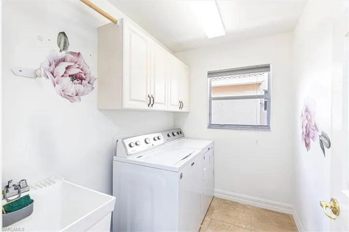 Washroom featuring light tile patterned flooring, separate washer and dryer, and cabinet space