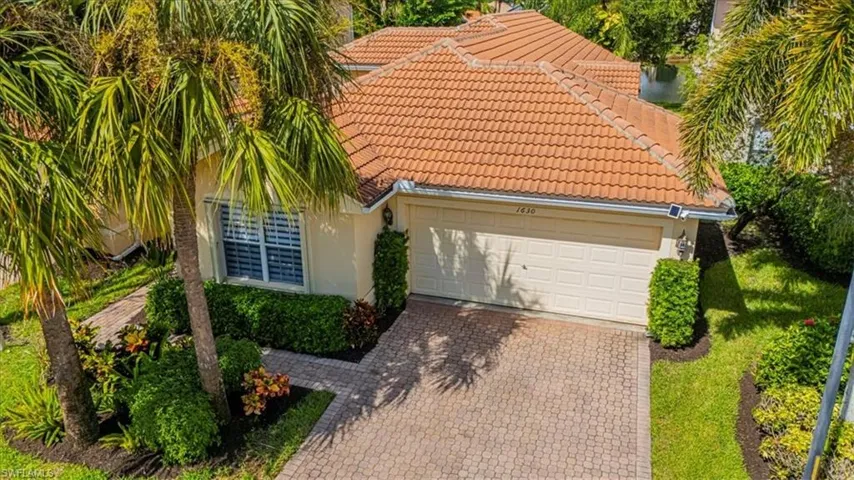 View of front of home with stucco siding, driveway, a tiled roof, and an attached garage