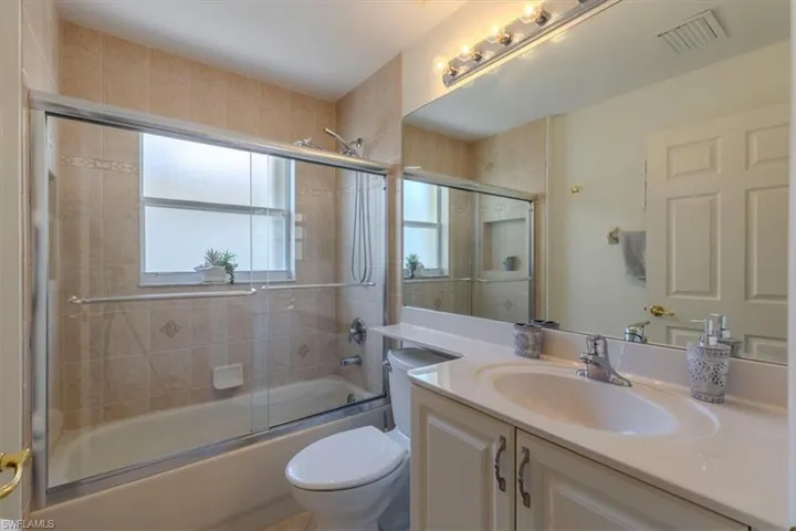 Bathroom featuring vanity and shower / bath combination with glass door