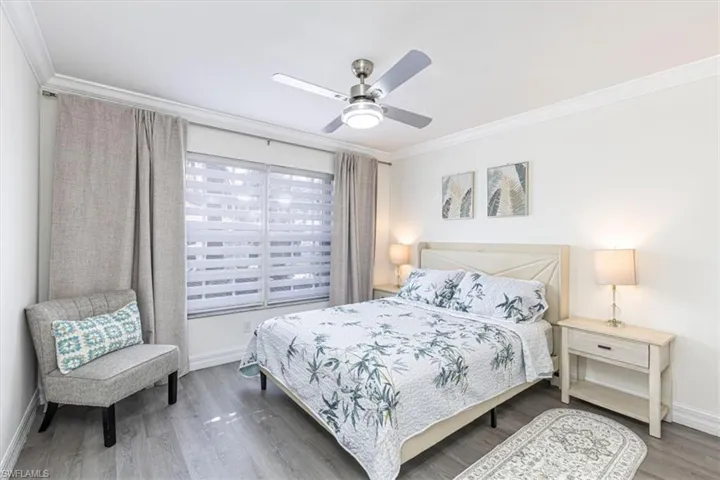 Bedroom with crown molding, wood finished floors, and a ceiling fan