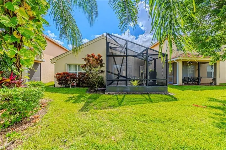 Rear view of property featuring stucco siding, a sunroom, a yard, and glass enclosure