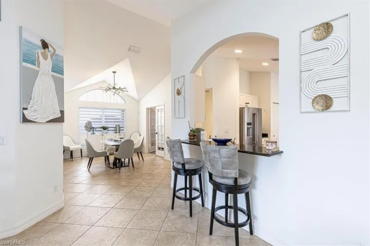Kitchen with a breakfast bar area, high vaulted ceiling, dark countertops, high quality fridge, and arched walkways